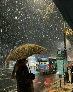 people walking in the rain with umbrellas on a city street as buses pass by