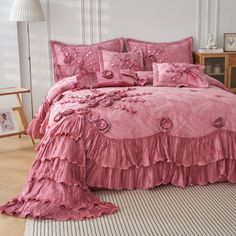 a pink bed with ruffled bedspread and matching pillow cases in a bedroom