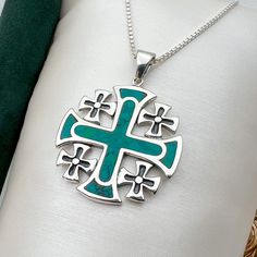 a green and silver cross on a white pillow