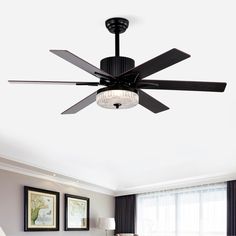 a living room with a ceiling fan and two pictures on the wall above the couch