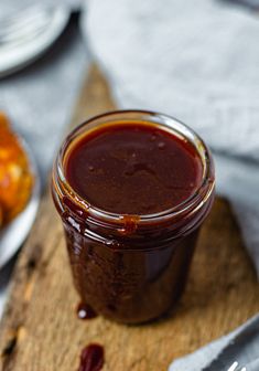 a jar of bbq sauce sitting on top of a cutting board next to some food