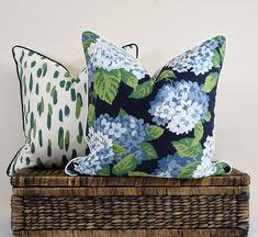 two blue and green pillows sitting on top of a wicker basket