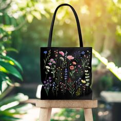 "Introducing our stunning black tote bag adorned with a beautiful wildflower design. This tote bag is not only a fashionable accessory but also a functional companion for your daily adventures. The captivating wildflowers printed on the bag exude a sense of natural beauty and freedom, making it a perfect choice for nature lovers and those who appreciate the enchantment of the outdoors. Crafted with durable and high-quality materials, this tote bag is designed to withstand the demands of your busy lifestyle. Its spacious interior offers ample room for your essentials, whether you're heading to work, running errands, or enjoying a leisurely stroll in the park. The sturdy handles ensure comfortable and convenient carrying, while the black color adds a touch of elegance to your ensemble. This Black Tote Canvas Bag For Spring, Black Canvas Bag For Daily Use In Spring, Black Bags With Floral Print For Gifts, Black Floral Print Tote Bag, Everyday Black Bag With Floral Print, Handmade Black Bags For Spring, Black Shoulder Bag For Spring Gift, Eco-friendly Black Shoulder Bag Gift, Handmade Black Canvas Bag As Gift