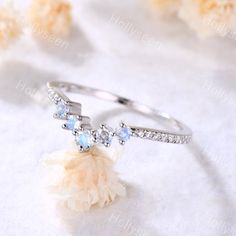 an image of a ring with stones and feathers on the table in front of flowers