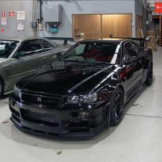 two cars parked in a garage next to each other on the floor and one is black