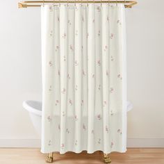 a white shower curtain with pink flowers on it in front of a bathtub and toilet