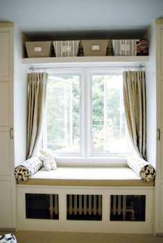 a window seat in the middle of a room with curtains and blankets on top of it