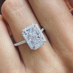 a close up of a person's hand with a diamond ring on their finger