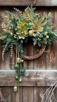 a wreath is hanging on the side of a wooden door with greenery and balls