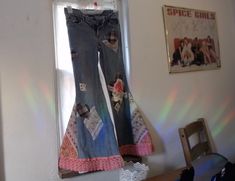 two pairs of jeans are hanging on the wall in front of a window with sunlight streaming through them