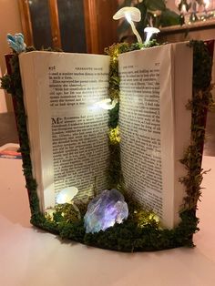 an open book sitting on top of a table with moss growing out of the pages