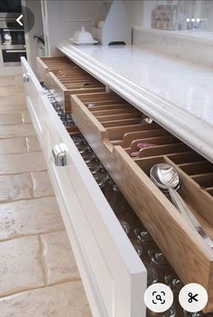 an open drawer in a kitchen with utensils and spoons on the drawers