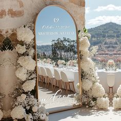 a large mirror sitting on top of a table covered in white flowers and greenery