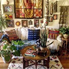 a living room filled with lots of plants and pictures hanging on the wall above it