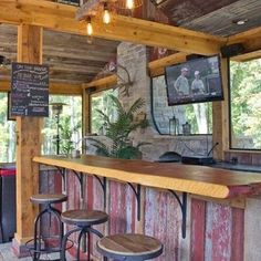 a bar with three stools in front of it and a television on the wall