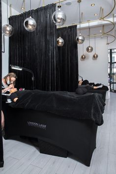 two women laying on top of a bed in a room with lights hanging from the ceiling