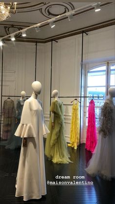 mannequins dressed in different colored gowns on display