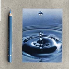 a blue pen sitting next to a water drop