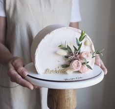 a person holding a cake with flowers on it