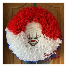 a clown face made out of red, white and blue paper flowers on a door