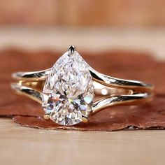 a close up of a ring with a pear shaped diamond on it's side