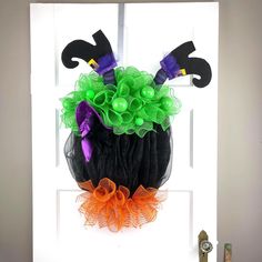 a door decorated for halloween with green and orange decorations on the top, black mesh wreath