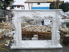 a large white marble fireplace surround surrounded by pallets