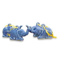 two small blue elephants with yellow ribbons on their trunks are facing each other in the same direction