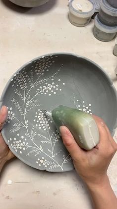 a person using a mouse on a gray plate with flowers and leaves painted on it