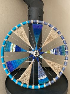 a spinning wheel made out of yarn sitting on top of a black table next to a wall