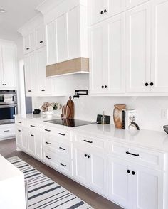 a kitchen with white cabinets and counter tops is pictured in this image, there are black and white striped rugs on the floor