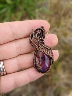 a hand holding a ring with a large stone in it's center and an intricate filigree design on the front