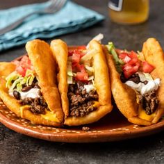 three tacos sitting on top of a brown plate