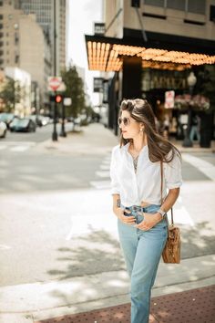 a woman is standing on the sidewalk with her hand in her pocket