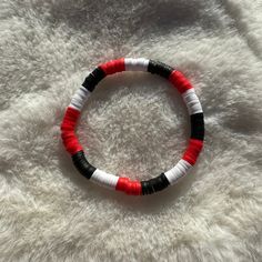 Handmade bracelet featuring red, black, and white heishi clay beads. This bracelet is ideal for showcasing your school spirit, whether it be for your high school or college. It's a great way to support your favorite college teams like the Georgia Bulldogs or the NC State Wolfpack. The bracelet is stretchy for easy wearing. Size of bracelet in photo: 7 1/2 inches Red Black White Bracelet, School Clay Bead Bracelet, Red Clay Bead Bracelet Ideas, Clay Bead Bracelet, Nc State Wolfpack, Clay Bracelet, Beaded Jewelry Designs, Clay Bead, Black Clay