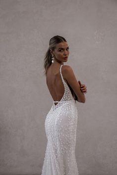 a woman in a white wedding dress is standing with her back to the camera