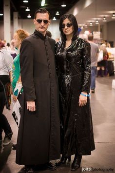 two people dressed in black standing next to each other