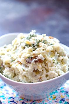 a white bowl filled with mashed potatoes on top of a blue and yellow place mat