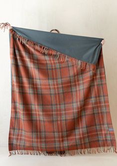 an orange plaid blanket with fringes hanging from it's sides on a white wall