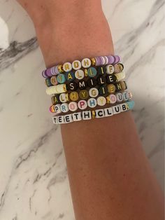 a woman's arm with four bracelets that say smile and toothbrush club