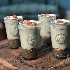 four desserts in glass cups on a wooden table