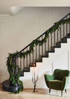 a green chair sitting in front of a banister next to a stair case with greenery on it