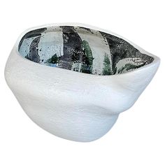 a white bowl with black and green designs on the inside is sitting in front of a white background