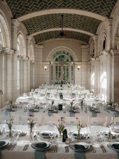 a banquet hall with tables and chairs set up for an event or function, in front of large arched windows