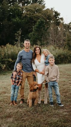 a family posing for a photo with their dog and two children in a field at sunset