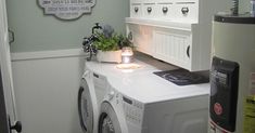 a washer and dryer in a small room with white cupboards on the wall