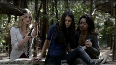 three women sitting on a swing in the woods