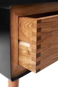 a close up of a wooden drawer on a black cabinet with wood handles and knobs