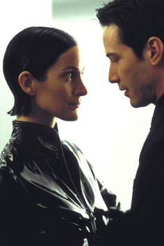 a man and woman standing next to each other looking at each other's eyes