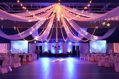 a large room with white drapes and lights on the ceiling is decorated for an event